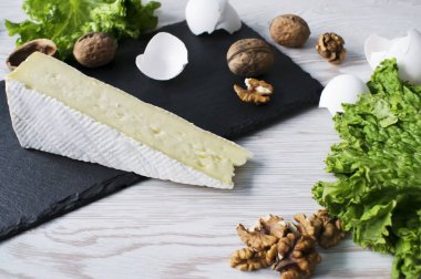 Peynir brie, fındık ve verdure ahşap bir masa üzerinde. Üstten görünüm.