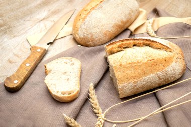 Bir somun taze ekmek ve ahşap zemin üzerinde kesilmiş baget dilimi bıçak ve fotokopi alanı, yakın çekimde pişmiş hamur işi..