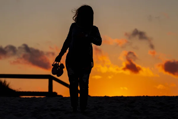 Silhouette of girls with sandals at sunset — Stock Photo, Image