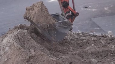 Kazı kovası şehre kum döküyor.