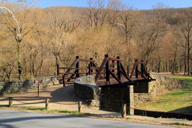 A pedestrian bridge leads visitors to Virginius Island, located in the Potomac River and site of numerous old industrial ruins, Harper Ferry National Historical Park in the state of West Virginia clipart