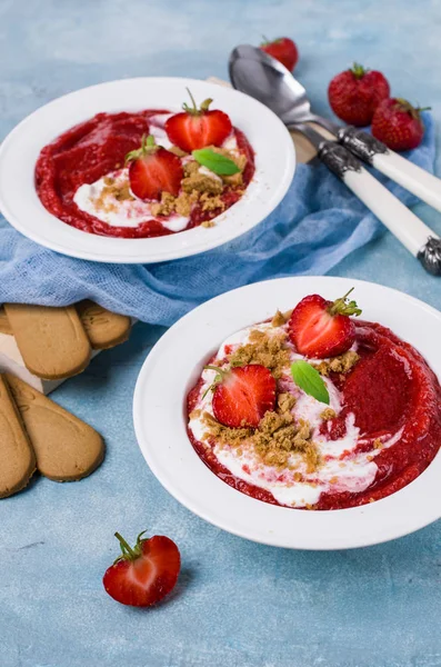 Mashed red berries with cream and cookies. Selective focus.