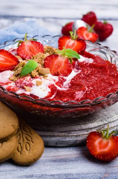 Mashed red berries with cream and cookies. Selective focus.