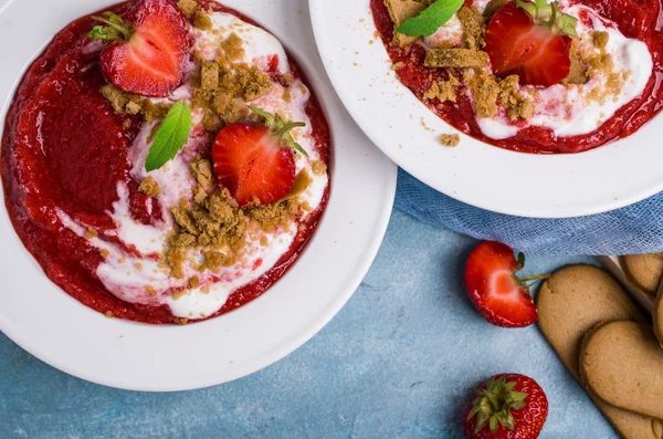 Mashed red berries with cream and cookies. Selective focus.