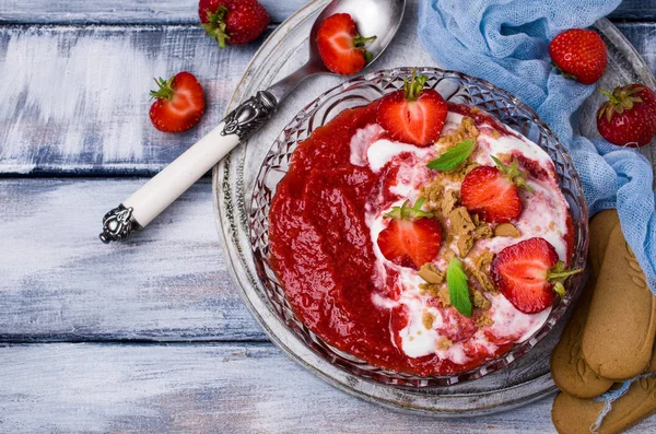 Mashed red berries with cream and cookies. Selective focus.