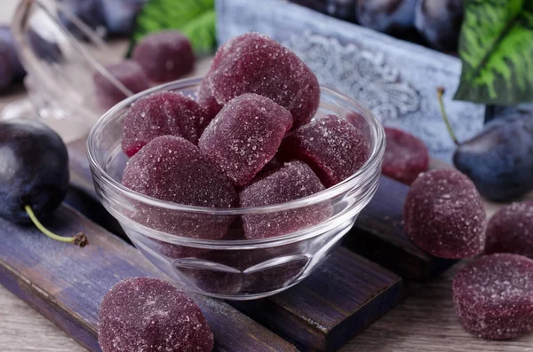 Plum jelly candies in sugar on wooden background. Selective focus.