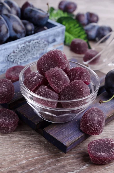 Plum jelly candies in sugar on wooden background. Selective focus.
