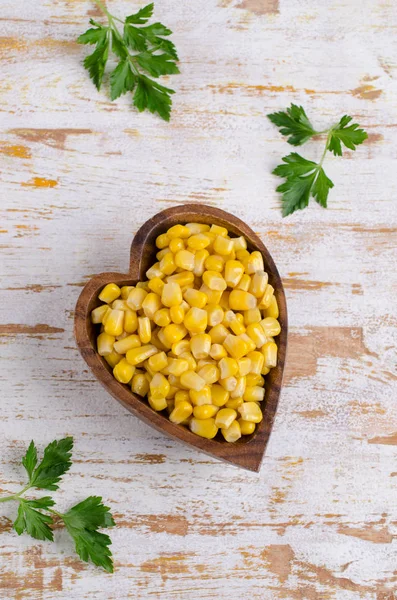 Sweet canned corn in a dish on a wooden background. Selective focus.