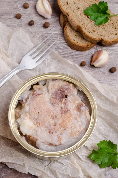 Canned meat fillet in a metal can on a wooden background. Selective focus.