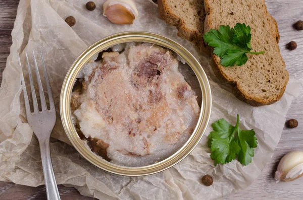 Canned meat fillet in a metal can on a wooden background. Selective focus.