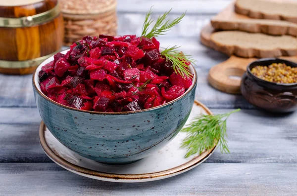 Traditional salad of boiled vegetables with sauerkraut in a bowl on a wooden background. Selective focus.