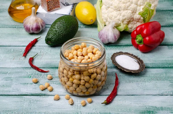 Canned chickpeas in a glass jar on a wooden background. Selective focus.