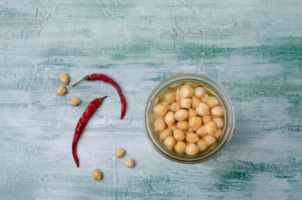Canned chickpeas in a glass jar on a wooden background. Selective focus.