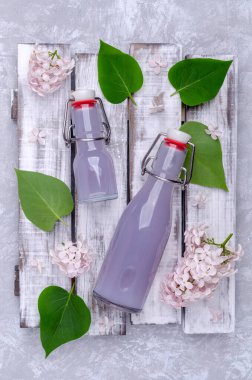 Gri arka planda bir bardakta leylak içkisi. Seçici odak.