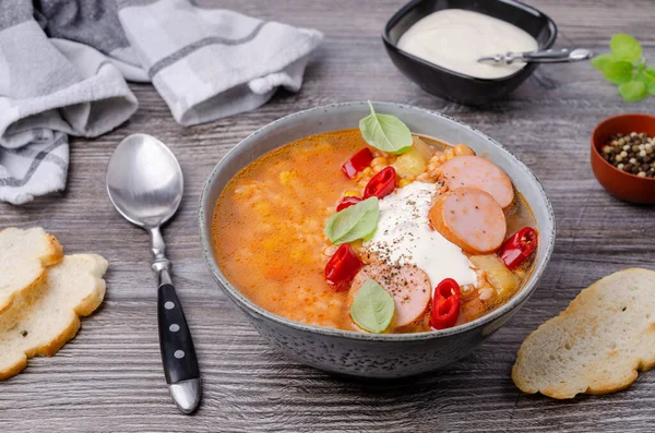 Soup with rice and beans, sausages and vegetables on a wooden background. Selective focus.