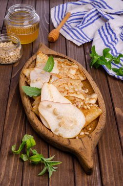 Armutlu krep, fındık ve bal, ahşap arka planda bir tabakta. Seçici odak.