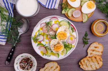 Ahşap zemin üzerinde çiğ sebzeli ve yumurtalı soğuk çorba. Seçici odak.