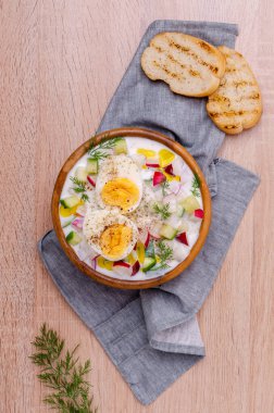 Ahşap zemin üzerinde çiğ sebzeli ve yumurtalı soğuk çorba. Seçici odak.