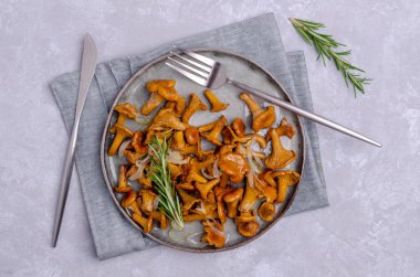 Kızarmış mantarlı, soğanlı, biberiyeli ve gri arkaplanlı. Seçici odak.