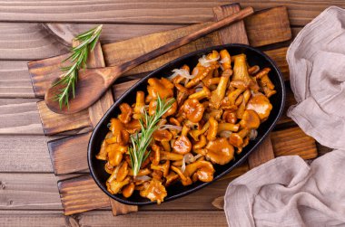 Koyu ahşap zemin üzerinde soğanlı ve biberiyeli mantar kızartması. Seçici odak.