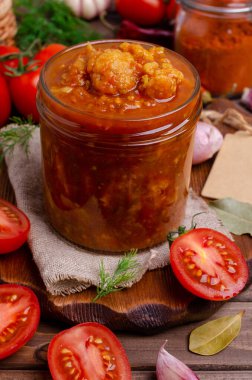 Koyu ahşap arka planda domates soslu sebzeli konserve karnabahar. Seçici odak.