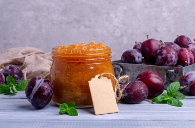 Cam kavanozdaki sarı erik reçeli mavi ahşap arka planda taze meyveli. Seçici odak.