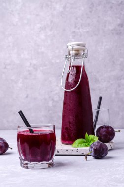 Taze meyveli gri bir arka planda cam içinde kırmızı erik suyu. Seçici odak.