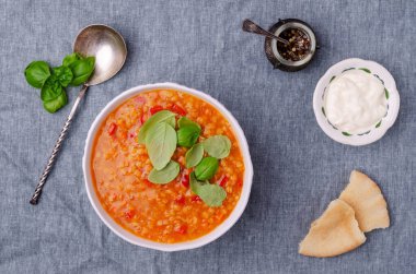 Mavi tekstil arka planında bir tabakta mercimek ve sebzeli kalın çorba. Seçici odak.