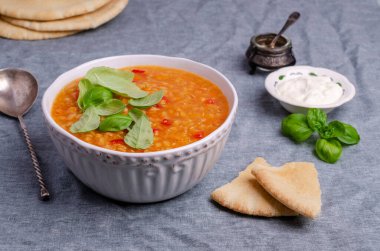 Mavi tekstil arka planında bir tabakta mercimek ve sebzeli kalın çorba. Seçici odak.