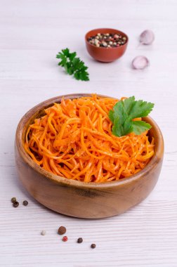 Hafif ahşap zemin üzerinde bir tabakta kesilmiş baharatlı havuç salatası. Seçici odak.