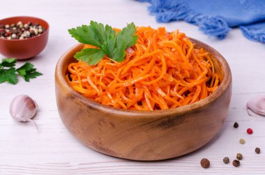 Hafif ahşap zemin üzerinde bir tabakta kesilmiş baharatlı havuç salatası. Seçici odak.