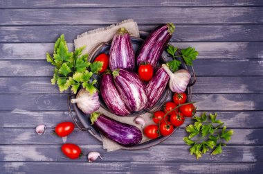 Gri ahşap arka planda metal bir tabakla çiğ sebzeler. Seçici odak.