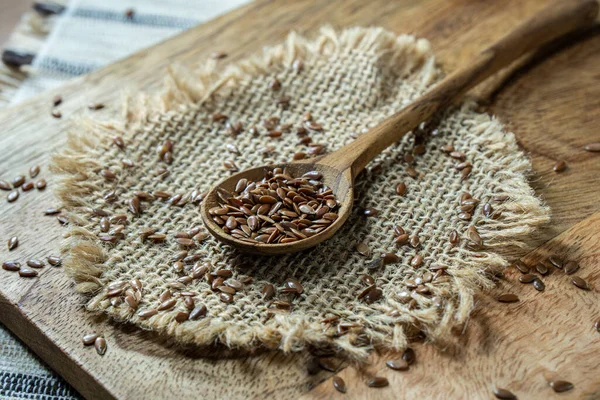 Flax seed inside wooden spoon on rustic table. Flaxseed is an organic and healthy grain packed with natural nutrients often used in a vegetarian diet.