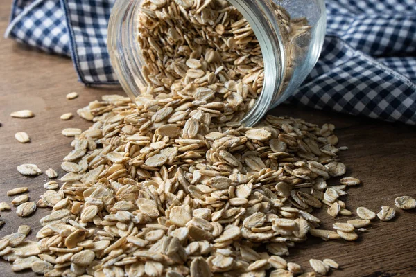 早餐燕麦从玻璃瓶掉到乡村餐桌上 燕麦是一种天然而健康的麦片 常用于素食 — 图库照片