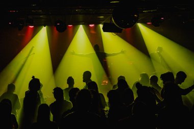 Barcelona'da bir gece müzik gösterisinde yeşil ışıkla dans eden insan kalabalığı