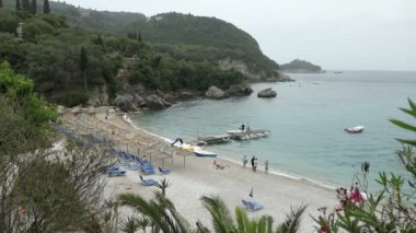 Liapades, Corfu / Yunanistan 23 Mayıs 2018: Vier Liapades Cennet plaj üzerinde. Sahilde oturan insanlar. Dağlar ve her yerde otel. (Corfu, Yunanistan)