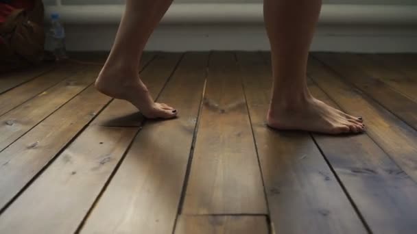 The girl is walking on the wooden floor. Female feet go on the wooden floor. — Stock Video