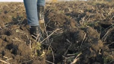 Kız sürülmüş alan yürüyor. Kadın ayakları yere yürüyor