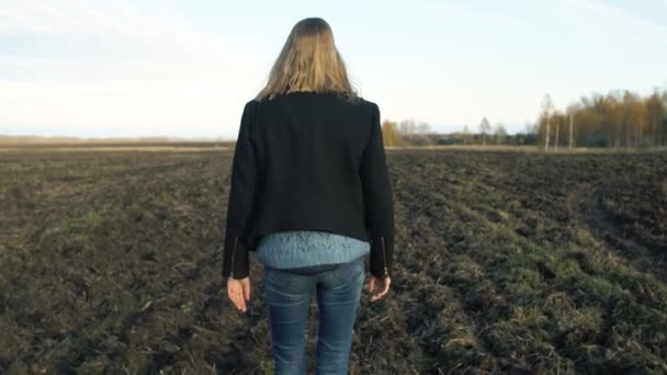 Une fille en manteau noir marche sur le sol, tristesse d'humeur d'automne — Video