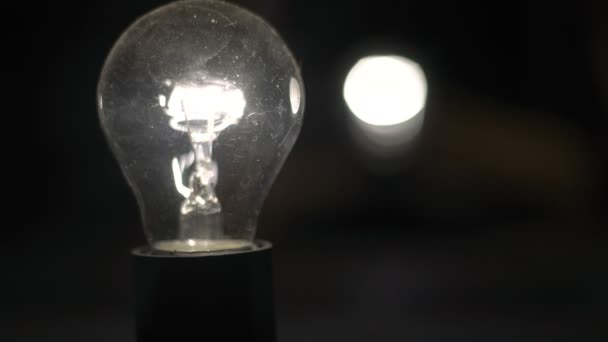 Glödlampan pulserar mot en svart bakgrund, pulsering av glödlampsljus, dimmern — Stockvideo