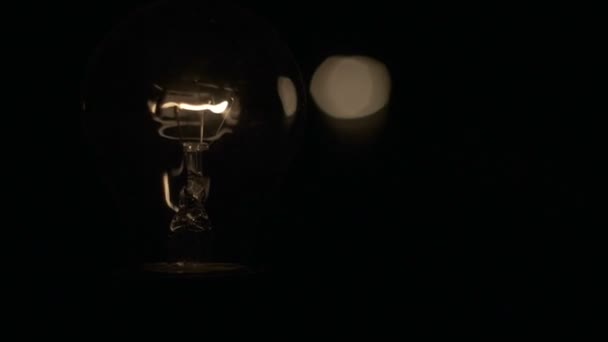 La lampadina pulsa su uno sfondo nero, la pulsazione della luce incandescente, il dimmer — Video Stock