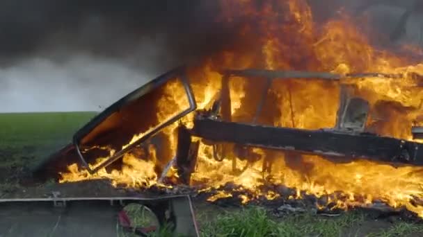 The burning car is in the field, the blown up car is on fire, the car is burning in slow motion — Stock Video