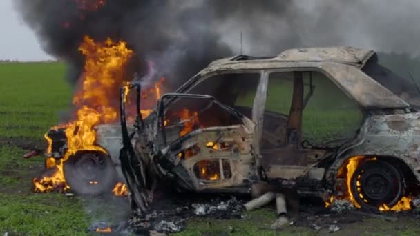 Палаючий автомобіль у полі, підірвана машина підпалена, машина горить у повільному русі — стокове відео