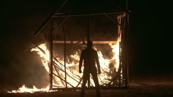 Un homme se tient dans une maison en feu, un homme contre une maison en feu la nuit, Plan d'ensemble — Video