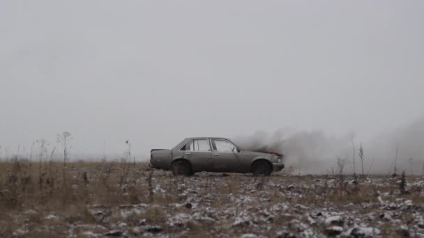 Auto explodiert, Seitenansicht, Auto brennt in einem grauen Feld — Stockvideo