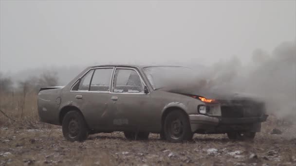 Auto s hořící motor je v poli, kouř vychází zpod kapoty vozu. — Stock video