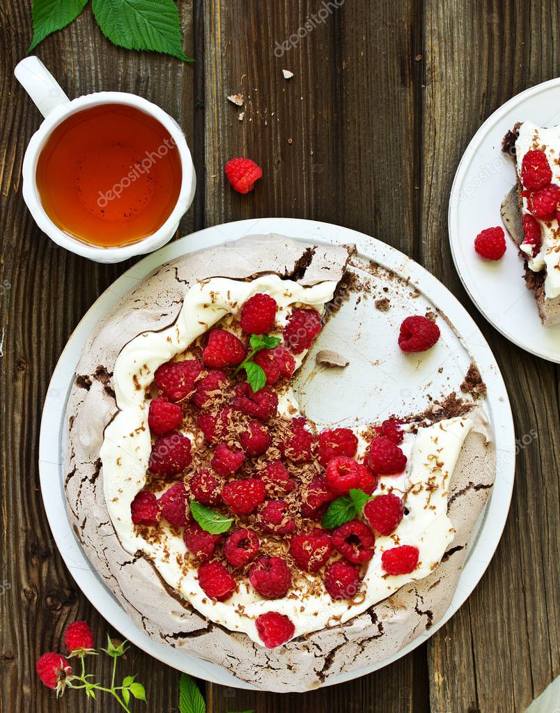 Chocolate dessert (pie) of pavlov with cream and raspberries.