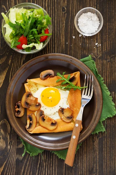 Pancakes with fried egg and fried mushrooms.