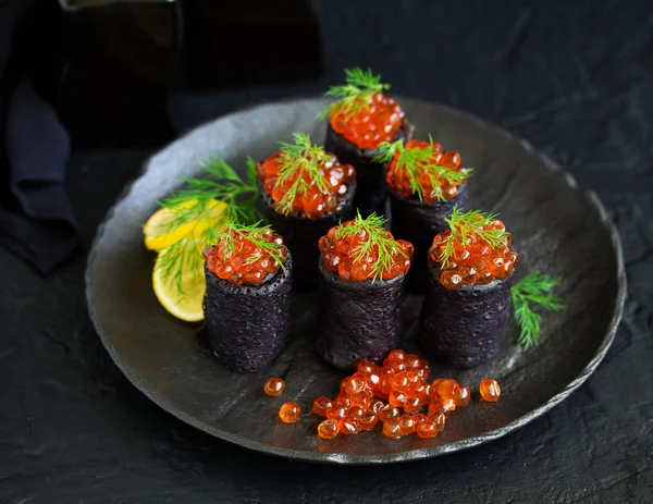 Pancakes with cuttlefish ink with red caviar. Russian kitchen.