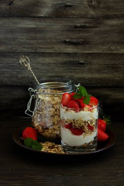 Granola, yoğurt ve çilekli bir bardakta tatlı. Yararlı bir kahvaltı..